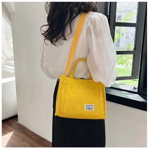 Detail of yellow corduroy crossbody bag with adjustable strap worn by model