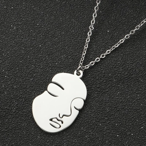 Macro detail of silver abstract face pendant with polished finish on black surface