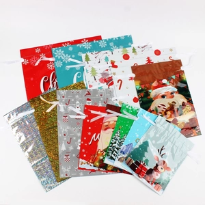 Variety of Christmas drawstring gift bags with Santa and reindeer patterns in multiple colors