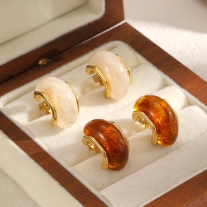 Vintage C-shaped resin amber and marble titanium steel earrings in a wooden jewelry box