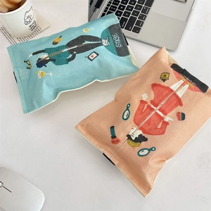 Close-up of linen fabric tissue holders with artistic illustrations in a desktop setting