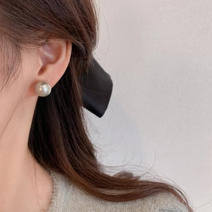 Close-up of a 10-12mm champagne pearl stud earring on a model with elegant styling