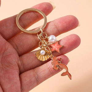 Detail of golden mermaid keychain with orange starfish and shell pendant with pearl
