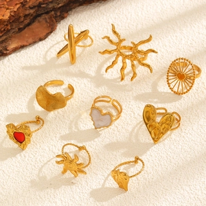 Flat lay of multiple gold heart and sun patterned rings on a white textured background