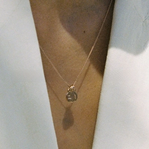 Close-up of gold stainless steel chain necklace featuring dual round letter pendants