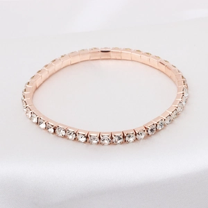 Macro shot of rose gold tennis bracelet with brilliant white zircons on white silk