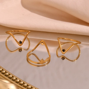 Detailed view of three minimalist 18K gold V-shaped rings with black micro-inlaid stones