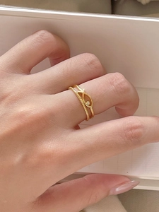 Detail of gold fish ring and twisted rope band set with small cubic zirconia stones
