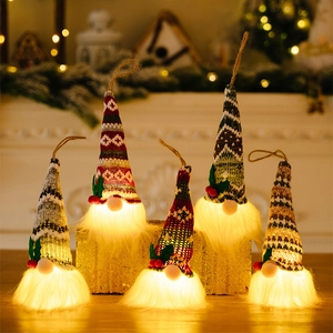 Group of five glowing Christmas gnomes with knitted hats and warm LED lights on wood