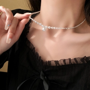 Nahaufnahme einer silbernen Halskette mit weißer Perle, getragen von einem Model
