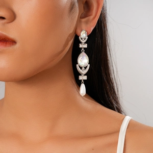 Close-up of geometric drop earrings with sparkling rhinestones and white pearls on model