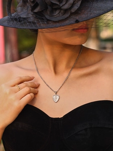Close-up of a silver heart pendant with keyhole design on a Cuban chain necklace