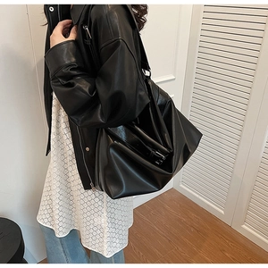 Vue détaillée du grand sac cabas en cuir souple noir porté à l'épaule par le mannequin