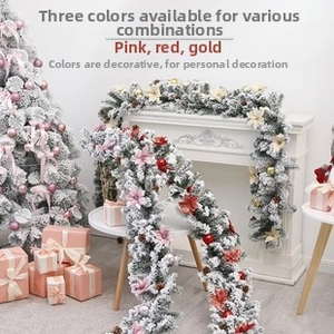Close-up of frosted Christmas garland with pink flowers and cones on a white fireplace