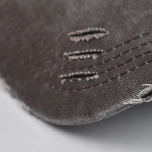 Macro detail of distressed cotton baseball cap showing frayed edges and triple stitching