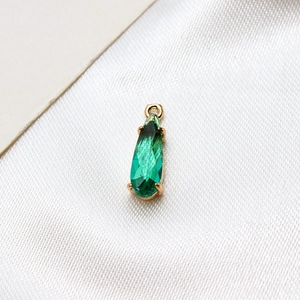 Detail of green teardrop faceted glass pendant with gold-plated claw setting and ring