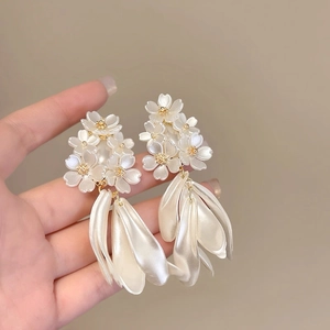 Macro detail of white flower earrings with gold stamens and pearl petal texture