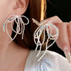 Detailed close-up of bow-shaped beaded earrings with colorful pearls and crystals