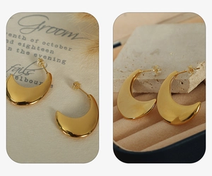 Detailed view of polished C-shaped 18K gold earrings on elegant vintage background