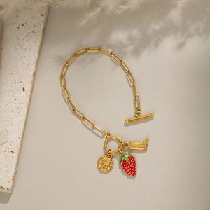 Détail du bracelet trombone doré 18 carats avec breloques fraise et coquille et fermoir toggle