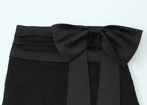 Detail of black satin bow waist decoration with intricate lace texture on mini skirt