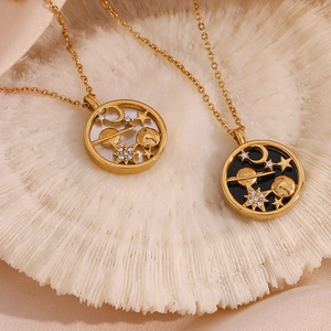 Close-up of gold celestial necklaces with moon and star pendants on a white shell