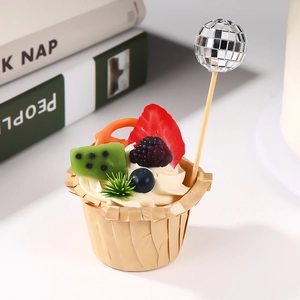 Close-up of a disco ball cake topper on a fruit cupcake for party decoration