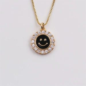 Detail of gold-plated smiley pendant with black enamel and sparkling zircon border