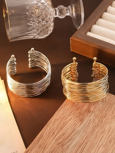 Detail of gold and silver multi-layer wavy C-shaped open bracelets on a vintage background
