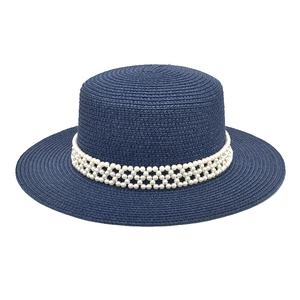 Detail of dark blue straw hat with elegant three-row pearl trim and fine woven texture