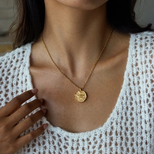 Close-up of 18K gold-plated stainless steel coin necklace with embossed bee pendant on model