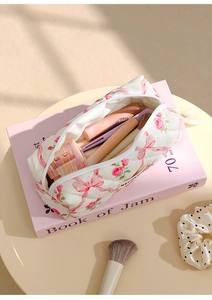 Quilted white makeup bag with pink bows and floral patterns filled with cosmetics