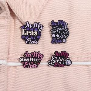Detailed view of four Taylor Swift themed enamel pins on pink denim fabric material