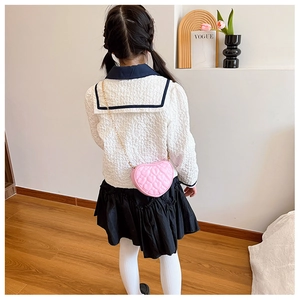 Detail of pink heart-shaped quilted handbag with elegant gold chain strap for kids