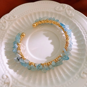 Detailed close-up of handmade gold wire-wrapped bracelet with light blue sea stones