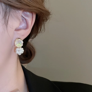 Detailed close-up of a model wearing floral pearl stud earrings with iridescent petals