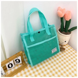 Close-up of mint green mesh travel tote with a secure snap button closure and woven label