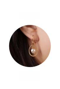 Close-up of a minimalist 18k gold hoop earring with a single round white pearl