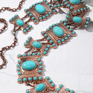 Close-up of bronze metal chain with engraved details and inlaid turquoise stones