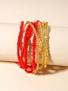 Detail of bohemian red and gold beaded body chain wrapped around a neutral cylinder
