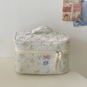 Close-up detail of quilted floral cosmetic bag with cute elephant patch and ribbon