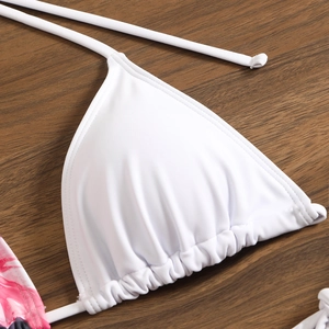 Detail of white triangle bikini top with ruched edges on dark wood background