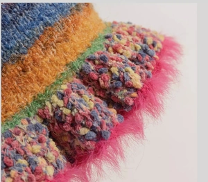 Detail of bohemian knit bucket hat with vibrant stripes and pink plush faux fur brim