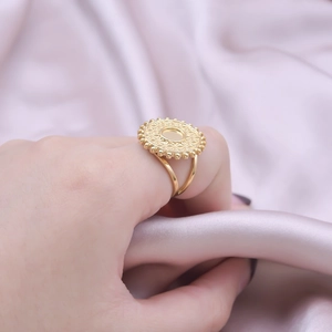 Close-up of a gold-plated stainless steel ring featuring a sunburst geometric engraving