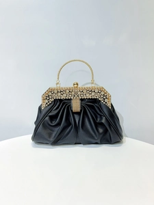 Detail of black pleated evening clutch with gold rhinestone frame and crystal top clasp