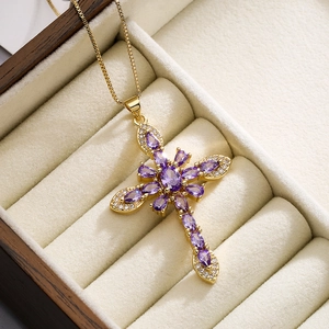 Macro shot of 18K gold plated cross pendant with purple crystals and white zircon details