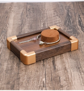 Detail of walnut wood jewelry tray with gold corners and velvet insert for necklace storage