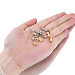 Irregular textured gold and silver spacer beads for DIY jewelry making on model's palm