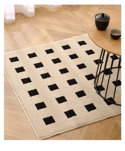 Detailed close-up of cream geometric rug texture on herringbone wood floor