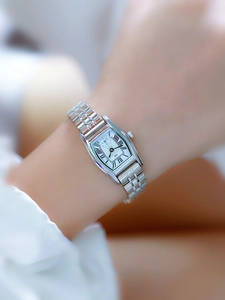 Detail shot of a silver tonneau watch with Roman numerals on a woman's wrist